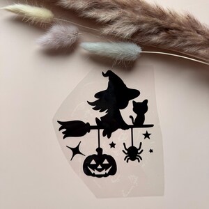 Könnte beinhalten: Schwarze Silhouette einer Hexe auf einem Besen mit einer Katze, Sternen, einer Spinne und einem Kürbis. Die Hexe trägt einen spitzen Hut. Das Design befindet sich auf einem klaren, leicht durchscheinenden Hintergrund.