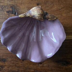 May include: A purple ceramic seashell dish with a brown seashell handle.
