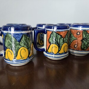 May include: Set of six small ceramic mugs with blue, yellow, green, and orange painted designs. The mugs have a traditional Mexican style.