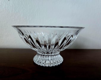 May include: A clear glass bowl with a pedestal base. The bowl has a decorative, faceted design.