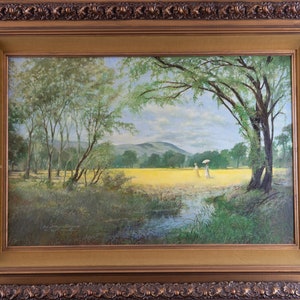 May include: A framed oil painting depicting a landscape scene with two figures walking in a field of yellow wildflowers. The figures are wearing white dresses and one is holding a white umbrella. The painting is set against a backdrop of green trees and a blue sky with white clouds.