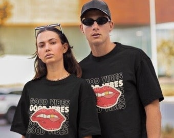 May include: Two people wearing black t-shirts with a red lips graphic and the text "Good Vibes" printed on them. The woman is wearing blue jeans and the man is wearing black pants.