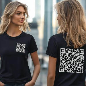 May include: Two people wearing black t-shirts with a white QR code printed on the front and back.