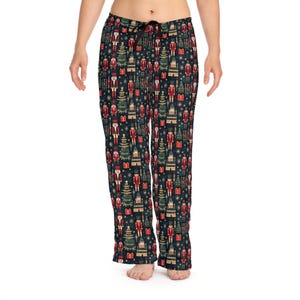 May include: Black pajama pants with a repeating pattern of nutcrackers, Christmas trees, and presents. The pattern is in shades of red, green, gold, and white.