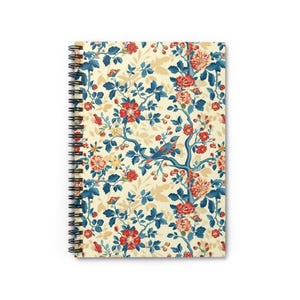 Puede incluir: Un cuaderno de espiral con un patrón floral que presenta flores rojas, azules y blancas y un pequeño pájaro azul en una rama. El fondo es de color crema claro.