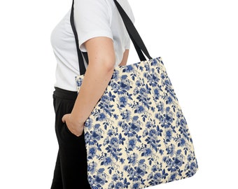 May include: A tote bag with a cream background and a blue floral pattern. The bag has black straps.
