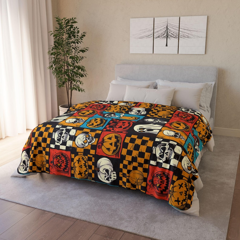 May include: A Halloween-themed fleece blanket with a patchwork design featuring orange, black and white checkered squares, jack-o'-lantern faces and skulls.