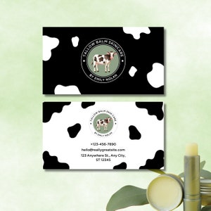 May include: A black and white business card with a cow illustration and the text "Tallow Balm Skincare by Emily Nolan". The card also includes contact information, including a phone number, email address, and physical address.