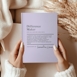 Könnte beinhalten: Ein lila Notizbuch mit dem Text "Difference Maker" und der Definition "Eine Person, die einen bedeutenden Einfluss hat, egal wie klein die Handlung oder die Worte sein mögen. Jemand, der Veränderung inspiriert, andere aufmuntert und einen Unterschied in der Welt um sie herum macht. Auch bekannt als: Samantha Lowes"
