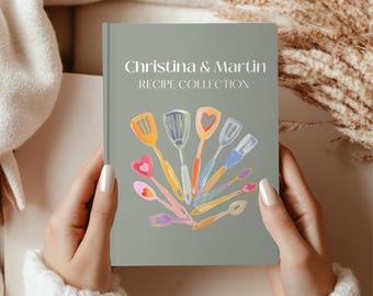 May include: A gray recipe book with the title "Christina & Martin RECIPE COLLECTION" in white text. The cover features a colorful illustration of kitchen utensils, including spatulas and spoons, arranged in a fan shape.