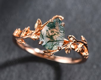 Puede incluir: Un anillo de oro rosa con una piedra preciosa de ágata verde engastada en un delicado diseño de hojas.