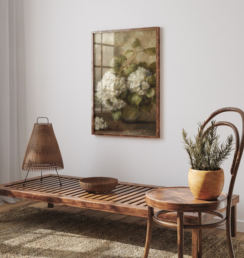 May include: A framed vintage botanical print of white hydrangeas in a vase, displayed on a white wall above a wooden bench and a small wooden stool.