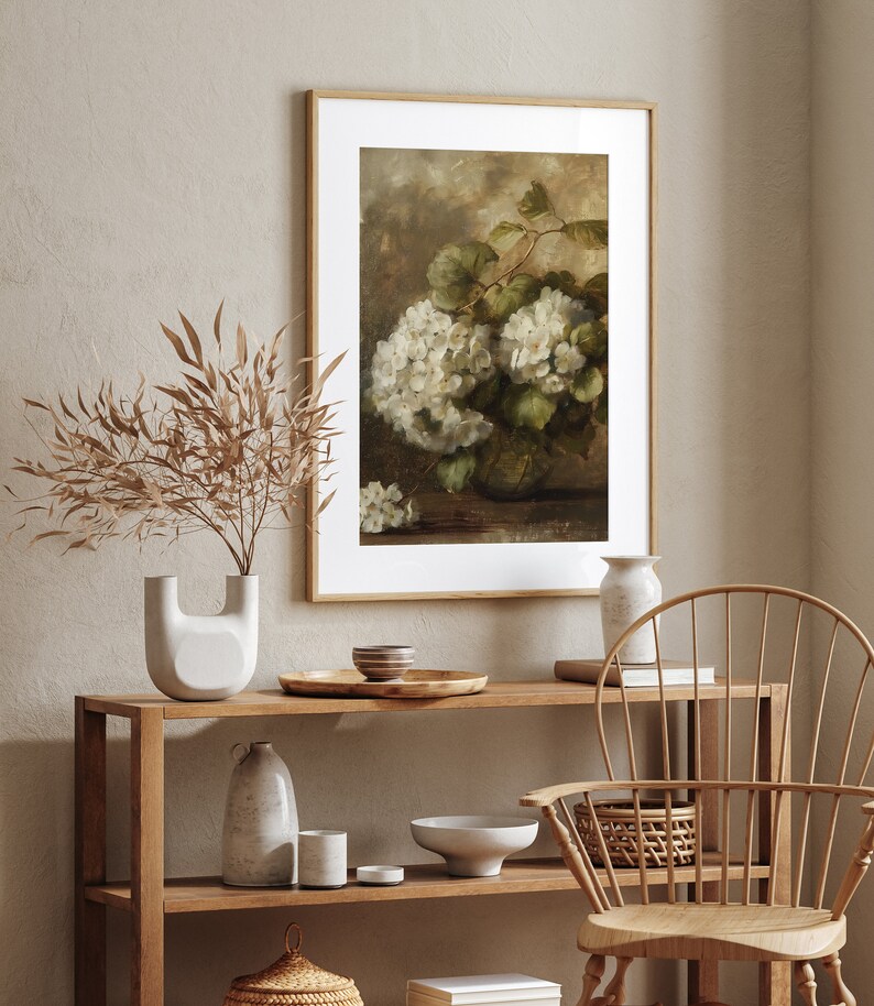 May include: A framed print of a still life painting featuring a bouquet of white hydrangeas in a vase. The painting is set against a brown background and has a vintage aesthetic.