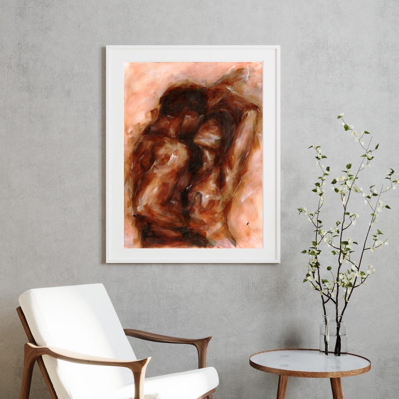 May include: Abstract painting in a white frame. The artwork depicts two figures in a warm color palette of browns and oranges. The figures are intertwined, suggesting intimacy. The painting is displayed in a modern interior setting.