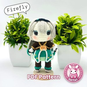May include: Crochet amigurumi pattern for a character with long white hair, a green dress, and brown boots. The pattern is called "Firefly" and is available as a PDF download. The image also includes a pink logo with a bunny and the text "Gatai".