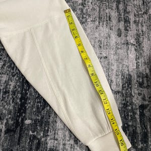 Pu&ograve; includere: Manica di felpa color crema con un metro a nastro giallo. Il nastro mostra una misura di circa 45 cm. La manica &egrave; realizzata in un materiale morbido e spesso.