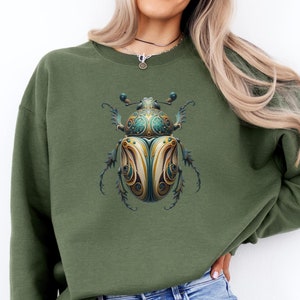 May include: A green sweatshirt with a graphic of a detailed, ornate, blue and gold beetle on the front.