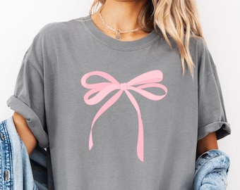 ピンクのリボンシャツ。キュートなコケットリボンTシャツ。ピンクのリボンリボントップ。快適なカラーのTシャツ。フェミニンなシャツ。ガーリーで美しいミニマリストのリボン。彼女へのギフト。