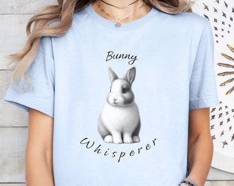 May include: A light blue t-shirt with a black and white illustration of a bunny rabbit and the text "Bunny Whisperer".