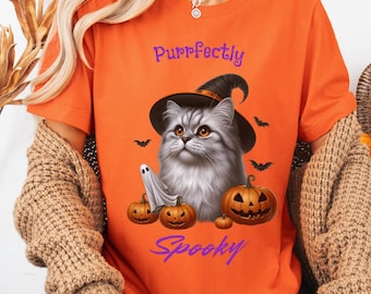 Puede incluir: Camiseta naranja con un diseño de Halloween. El gráfico muestra un gato gris con un sombrero de bruja, un fantasma y calabazas talladas. Las palabras "Purrfectly Spooky" están arriba y abajo de la ilustración del gato.