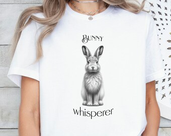 May include: White t-shirt with a black and white illustration of a rabbit and the text "Bunny whisperer".