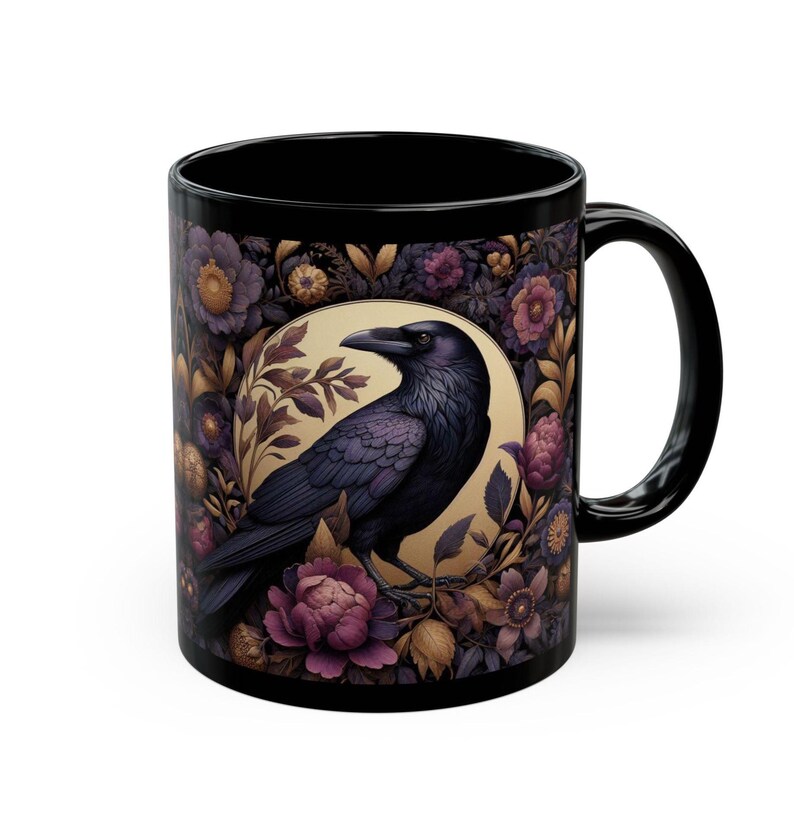 May include: Black ceramic mug featuring a detailed illustration of a raven perched within a floral design. The raven is depicted in shades of purple and black, surrounded by purple and gold flowers. The mug has a black handle and interior.