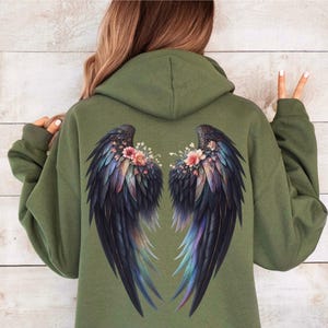May include: A green hooded sweatshirt with a black and iridescent angel wing design on the back. The wings are adorned with pink and white flowers.