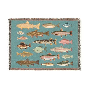 May include: A woven throw blanket featuring a teal background with various fish illustrations in shades of yellow, brown, and pink. The blanket has a fringed edge and a detailed pattern of different fish species.