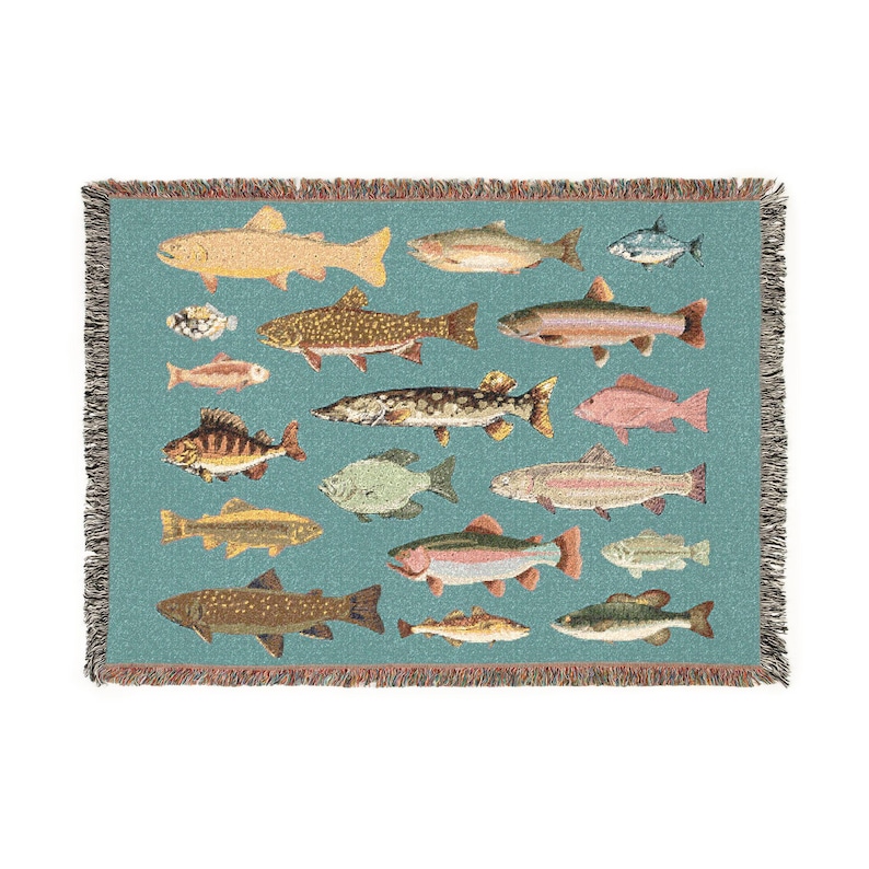 May include: A woven throw blanket featuring a teal background with various fish illustrations in shades of yellow, brown, and pink. The blanket has a fringed edge and a detailed pattern of different fish species.