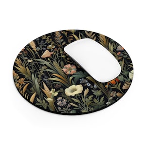 May include: A round black mouse pad with a floral design featuring a variety of flowers and leaves in shades of green, yellow, orange, and pink. A white computer mouse is sitting on the pad.