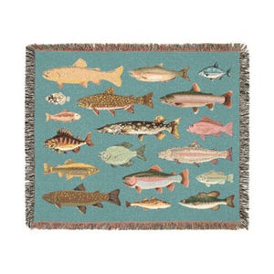 May include: A woven throw blanket featuring a teal background with various fish illustrations in shades of brown, yellow, and pink. The blanket has a fringed edge and is designed with a repeating pattern of different fish species.
