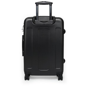 May include: Black suitcase with a retractable handle and four wheels. The suitcase is made of hard-sided material.