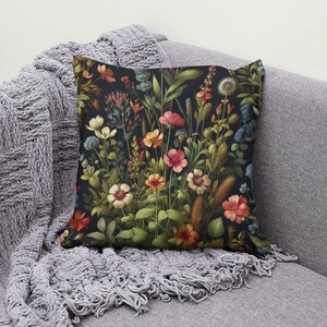 Peut inclure: Un coussin d&eacute;coratif avec un motif floral pr&eacute;sentant une vari&eacute;t&eacute; de fleurs color&eacute;es et de feuilles vertes sur un fond sombre.
