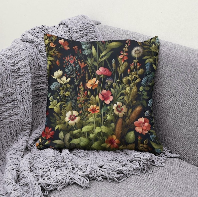 Peut inclure: Un coussin d&eacute;coratif avec un motif floral pr&eacute;sentant une vari&eacute;t&eacute; de fleurs color&eacute;es et de feuilles vertes sur un fond sombre.