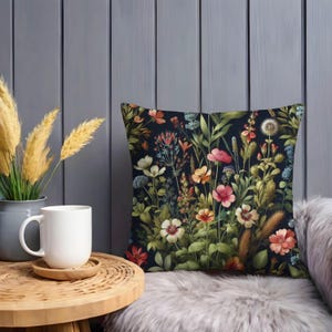 Peut inclure: Un coussin d&eacute;coratif avec un motif floral. Le coussin pr&eacute;sente une vari&eacute;t&eacute; de fleurs dans des tons de rose, rouge, jaune et bleu sur un fond bleu fonc&eacute;.