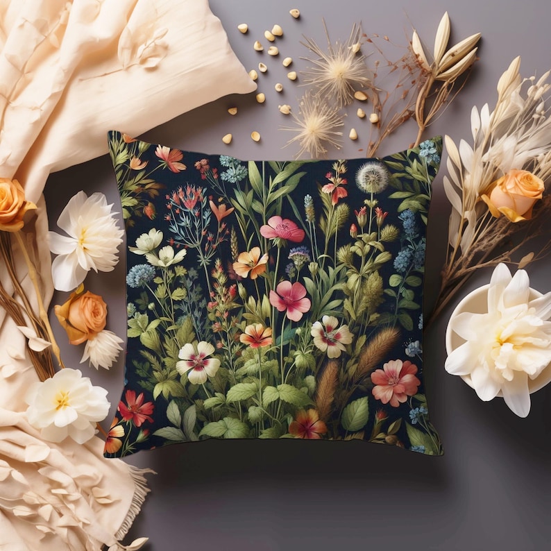 Peut inclure: Un coussin bleu fonc&eacute; avec un motif floral pr&eacute;sentant une vari&eacute;t&eacute; de fleurs color&eacute;es et de feuilles vertes. Le coussin est d&eacute;cor&eacute; de diff&eacute;rentes fleurs, notamment roses, rouges, jaunes et blanches.