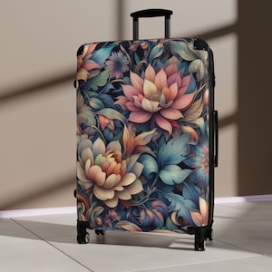 Puede incluir: Una maleta negra con un estampado floral con flores rosas, azules y amarillas. La maleta tiene un asa retráctil y cuatro ruedas.