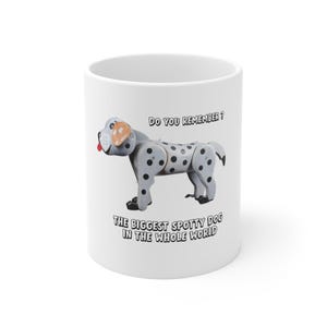 Puede incluir: Taza de cerámica blanca con un diseño de perro de dibujos animados. El perro es gris con manchas negras y una lengua roja. El texto en la taza dice "DO YOU REMEMBER?" y "THE BIGGEST SPOTTY DOG IN THE WHOLE WORLD".