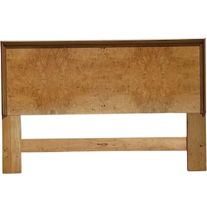 May include: A wooden headboard with a light brown wood grain finish. The headboard has a simple design with a rectangular frame and a single horizontal support beam.