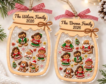 May include: Two personalized mason jar-shaped Christmas ornaments made of light wood and clear acrylic. Each features a red and white gingham bow, a jute hanging string, and gingerbread-style figures with names, plus the text The Wilson Family 2026 and The Brown Family 2026.