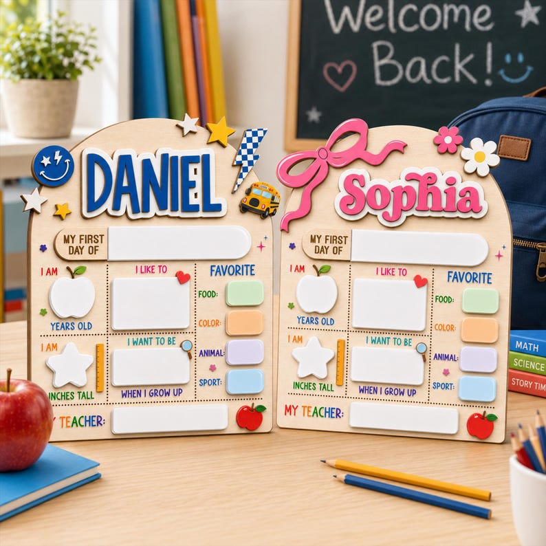May include: Two arched wooden school signs featuring the names Daniel and Sophia in blue and pink. Each sign includes sections for My First Day Of, I Am, I Like To, Favorite, and My Teacher, with icons like apples, stars, and a school bus.