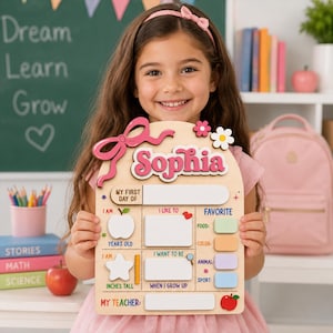 May include: A wooden arch-shaped sign with the name Sophia in pink letters at the top. The board features sections for My First Day Of, I Am, I Like To, Favorite, and My Teacher, with blank white spaces for writing details and colorful icons.