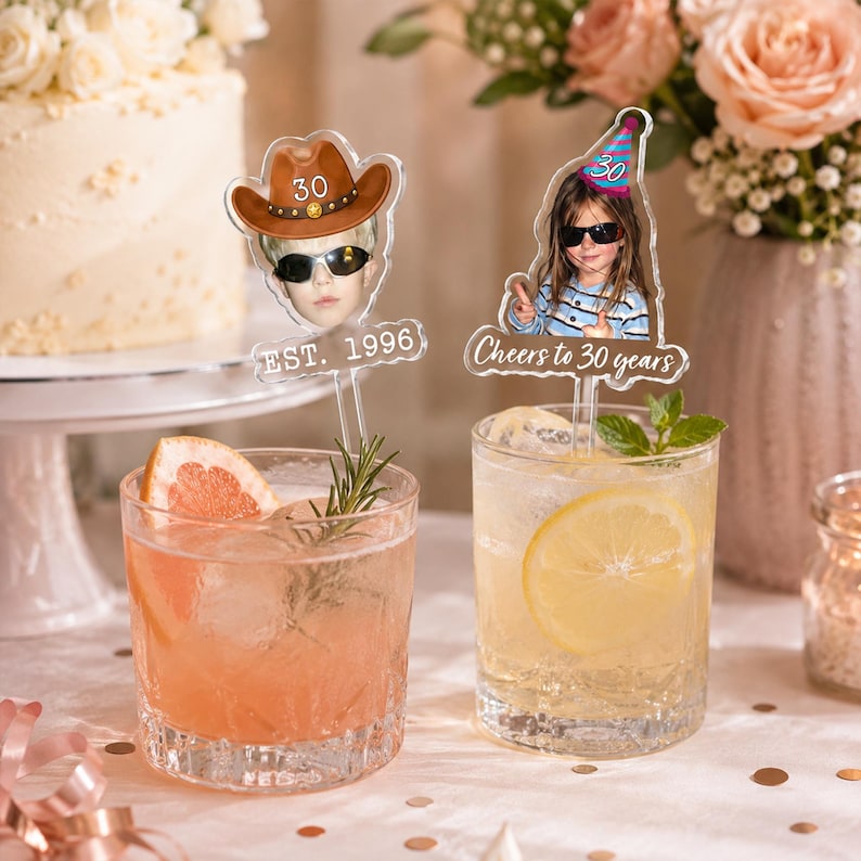 Puede incluir: Dos adornos acr&iacute;licos personalizados para bebidas con retratos fotogr&aacute;ficos. Uno muestra a una persona con sombrero de vaquero marr&oacute;n y el texto EST. 1996. El otro muestra a una persona con gorro de fiesta azul y el texto Cheers to 30 years.