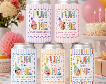 May include: Five cylindrical beverage can coolers with vertical striped patterns in purple, pink, blue, yellow, and rainbow colors. Each features a scalloped frame with the text "FUN to be ONE", a photo of a baby in a party hat, and event details.