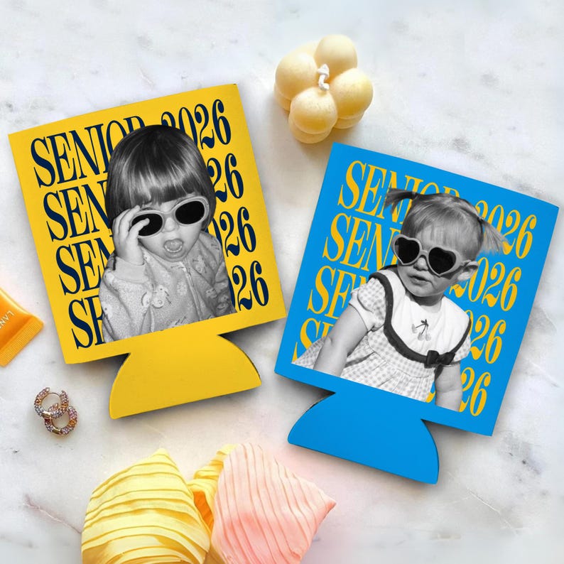 Puede incluir: Dos aislantes para bebidas, uno amarillo y otro azul, cada uno con una foto en blanco y negro de un ni&ntilde;o con gafas de sol. El texto "SENIOR 2026" est&aacute; impreso en amarillo en el aislante amarillo y en blanco en el azul. Tambi&eacute;n se ven una vela y accesorios.