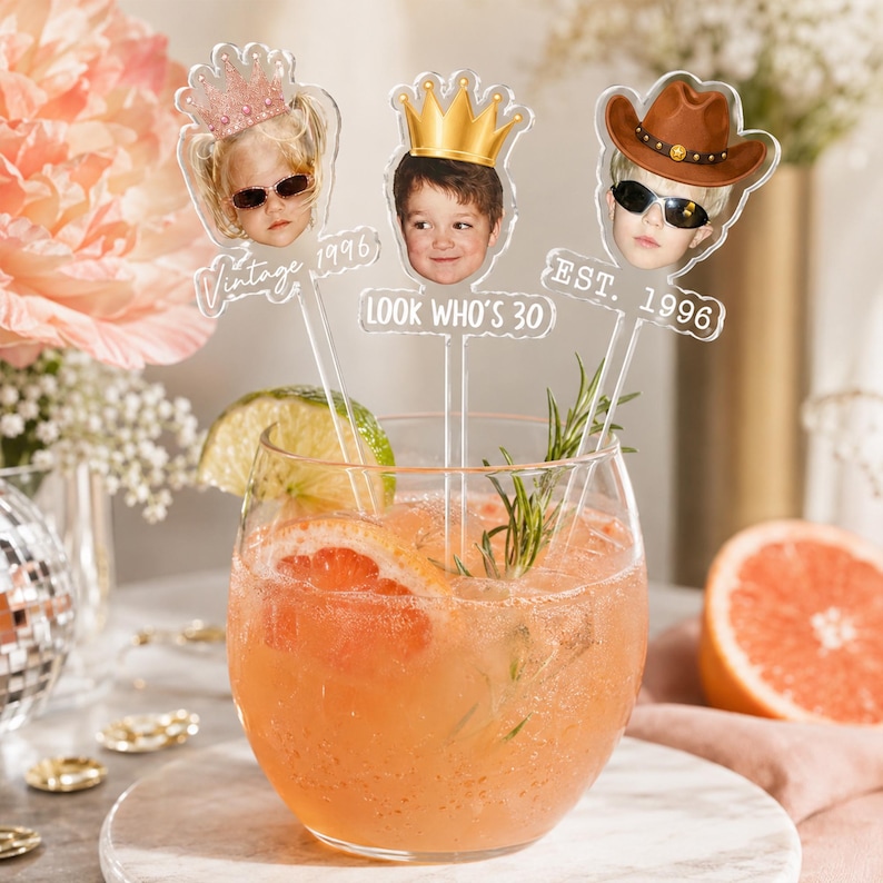 Puede incluir: Tres agitadores de bebidas de acr&iacute;lico transparente con recortes de fotos personalizados de rostros con una corona rosa, una corona dorada y un sombrero de vaquero marr&oacute;n. Incluyen texto blanco que dice Vintage 1996, LOOK WHO'S 30 y EST. 1996.