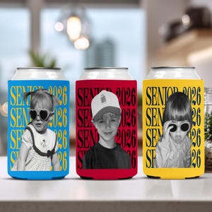 Puede incluir: Tres enfriadores de latas con fotos de ni&ntilde;os. Los enfriadores son azules, rojos y amarillos. Cada enfriador tiene la inscripci&oacute;n "SENIOR 2026" en un patr&oacute;n repetido. Las fotos son en blanco y negro.