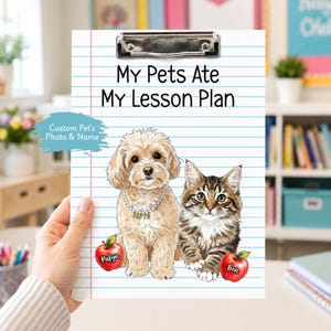 May include: A clipboard with the text "My Pets Ate My Lesson Plan." The design features a cartoon dog and cat, with the names "Pabyn" and "Ben" on apples. The clipboard has a metal clip and a lined paper background.