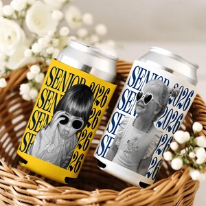 Puede incluir: Dos enfriadores de latas de aluminio con fotos de ni&ntilde;os con gafas de sol. Uno es amarillo con el texto "SENIOR 2026" en azul, el otro es blanco con el mismo texto en azul. Est&aacute;n en una cesta de mimbre.