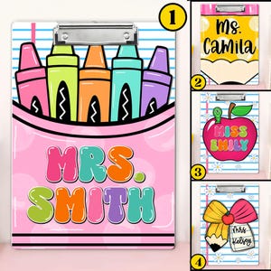 May include: A set of four clipboards with colorful designs. One clipboard features a pink crayon design with the text "MRS. SMITH." Other clipboards have pencil, apple, and bow designs with names. Each clipboard has a silver clip.